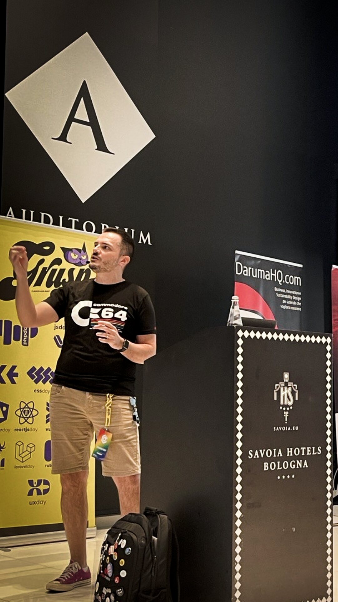 Presenting in a hotel auditorium wearing a Commodore 64 shirt.